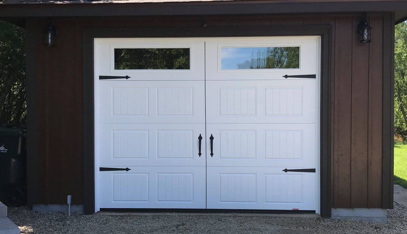 A white garage door featuring two windows, providing a clean and modern appearance to the exterior of a home.