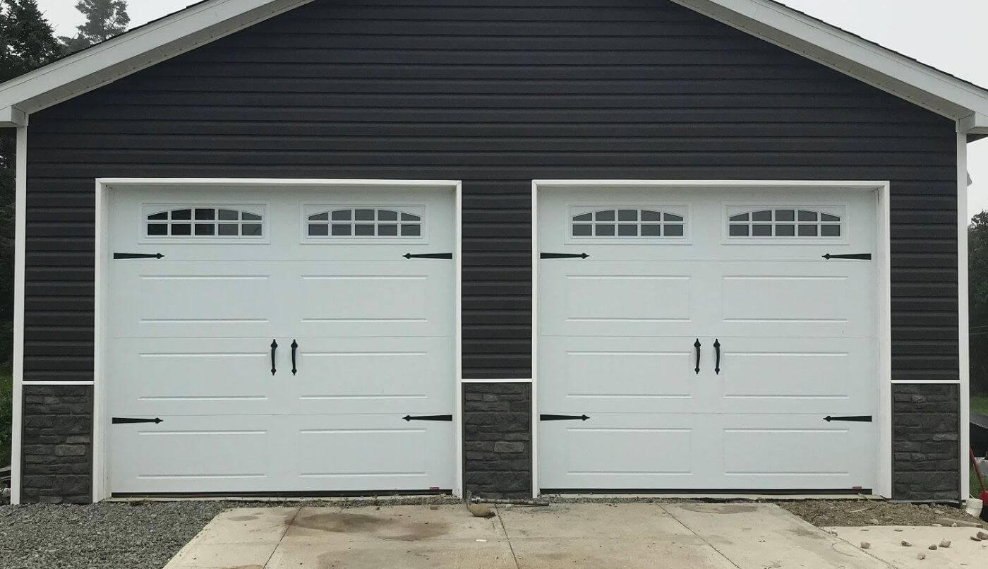 Two garage doors featuring windows, showcasing a modern and stylish exterior design.