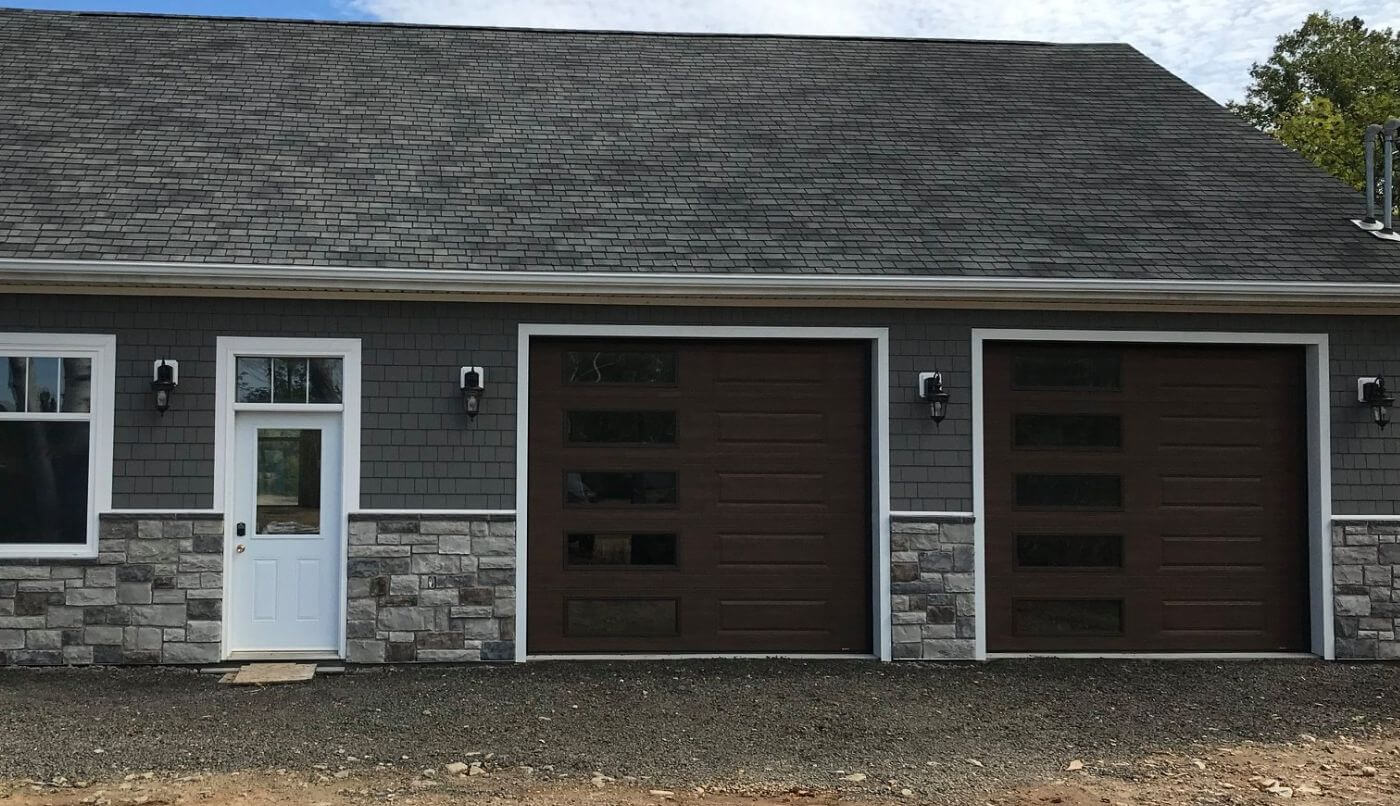A garage featuring two brown doors and a gray roof, set against a clear sky backdrop.